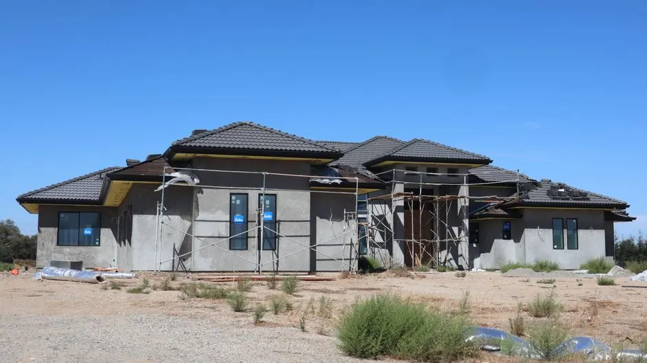 A modern house under construction on a clear day, showcasing progress and architecture.