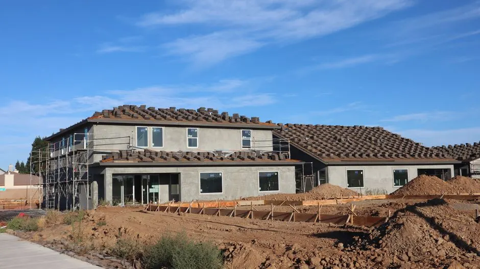 A modern suburban house under construction against a clear blue sky.