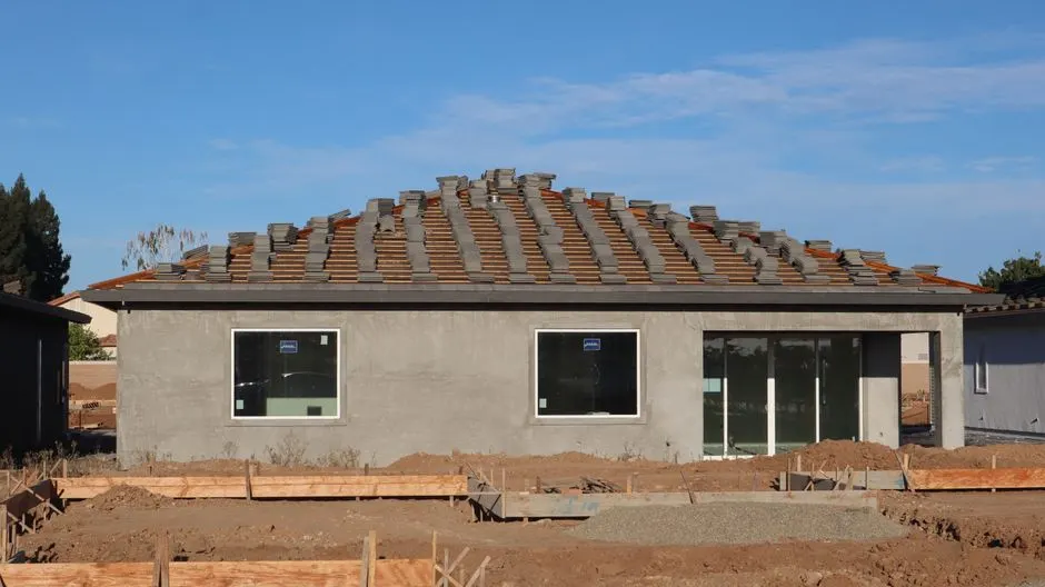 A new home under construction featuring a tiled roof and unfinished exterior.